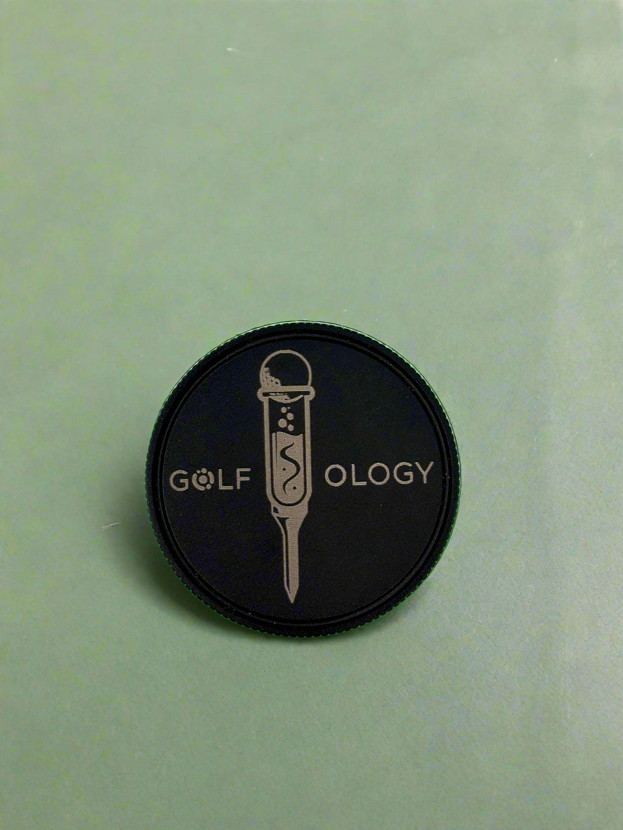 Black circular patch with 'GOLF OLOGY' text and microphone graphic on a light green background